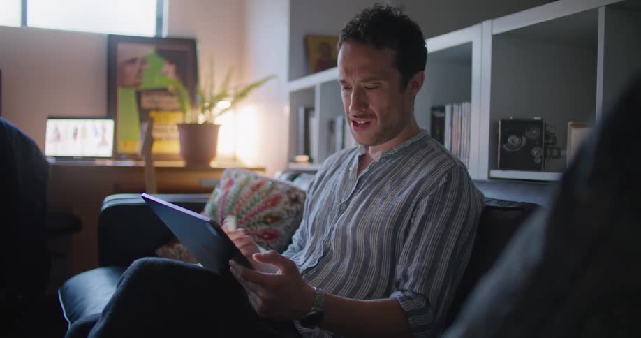 A man smiles as he talks and draws on a tablet during a video call