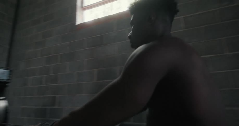 Muscular shirtless man works out in gym