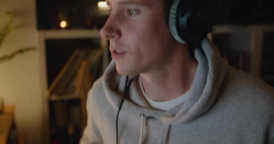 Man with black headphones and grey hoodie plays bass guitar