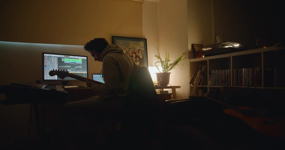 A man is playing the guitar at his desk