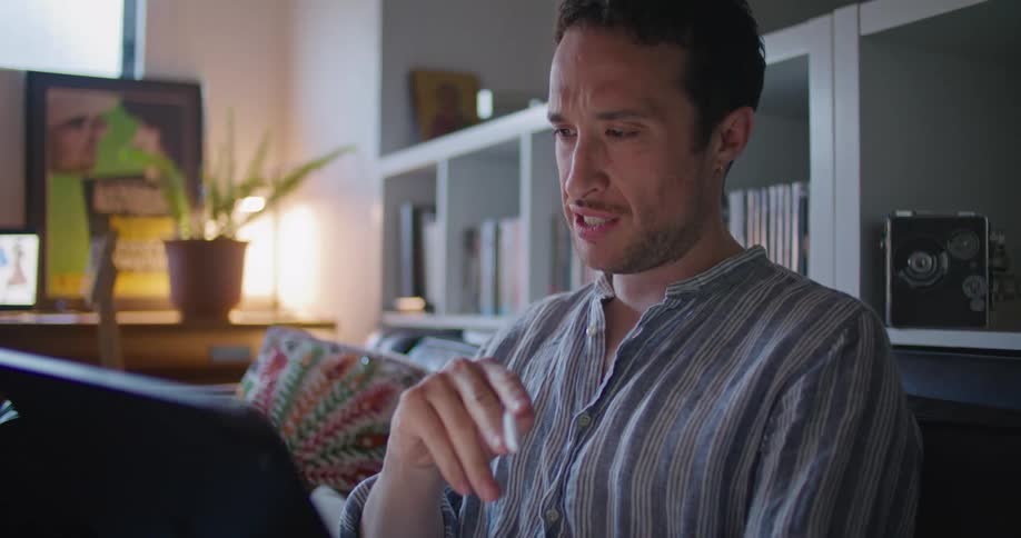 Man sitting on couch gestures while communicating via video conference