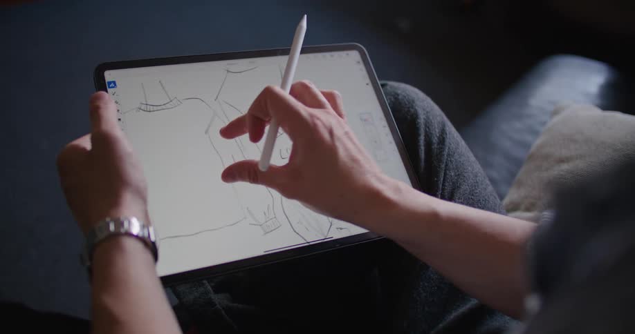 A person is sketching out designer clothing on a tablet