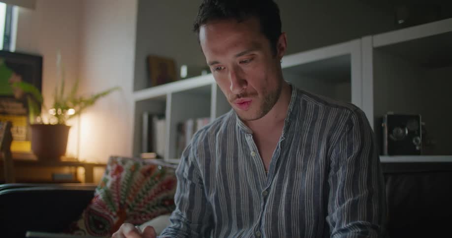 Man sits on couch sketching on tabletbacked by cubicle shelf
