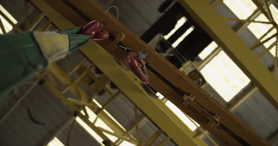 A close view of a canvas strap hanging from a hook inside a large warehouse during the day