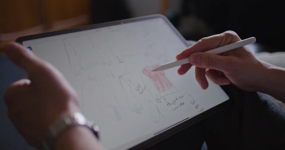 A person in a room using a stylus and tablet with a wall in the background