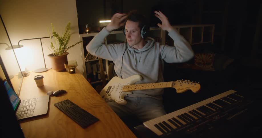 A man is playing the guitar at his desk