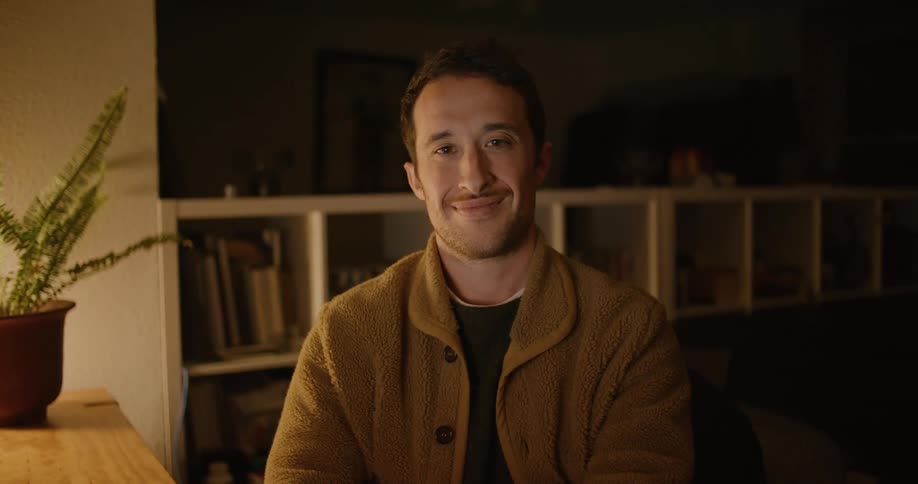 A man is sitting at his desk smiling