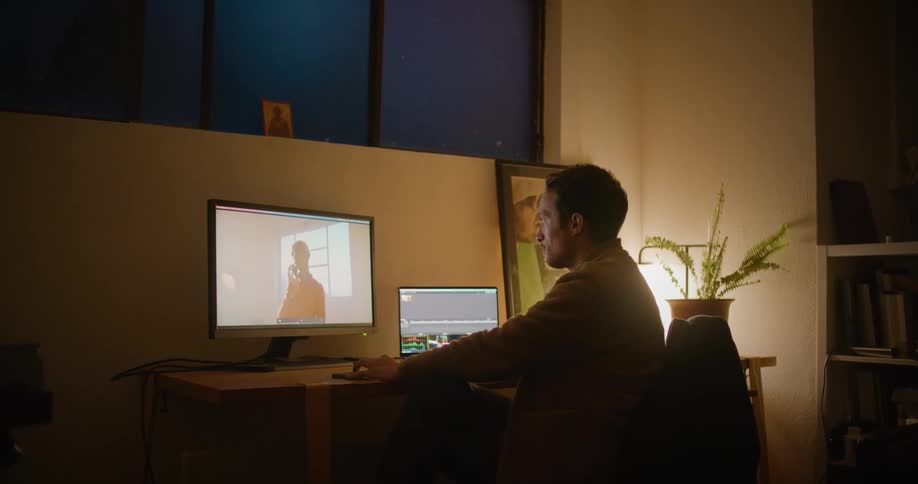 Man sits at table in dark office manipulating image on screen