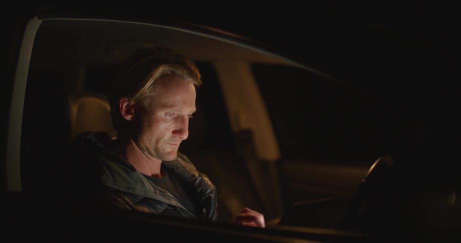 A man is looking at his cellphone in the car