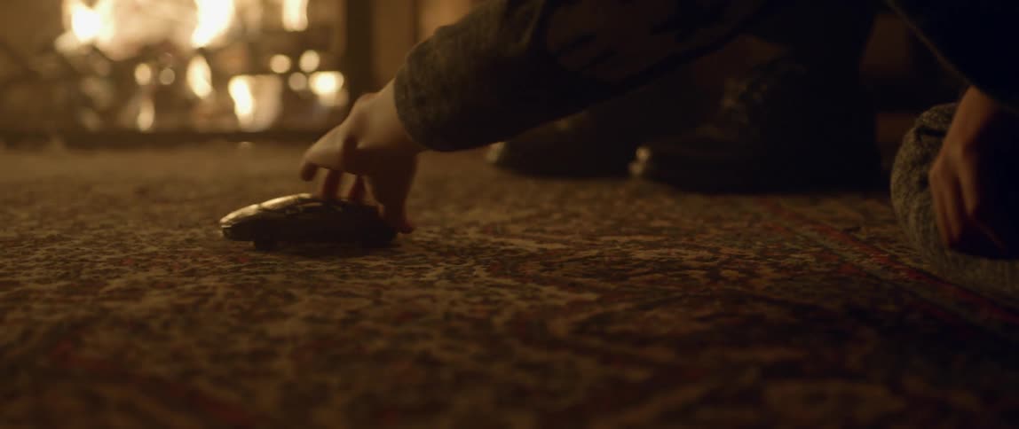 A child pushes a toy car across the carpet