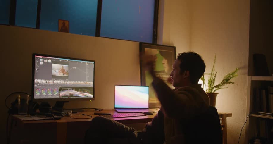 A man stretches as he sits in front of computers