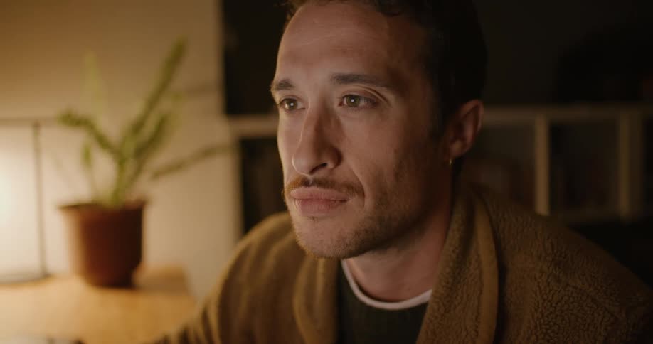 A man sighs and rubs his mouth as he is looking at a computer