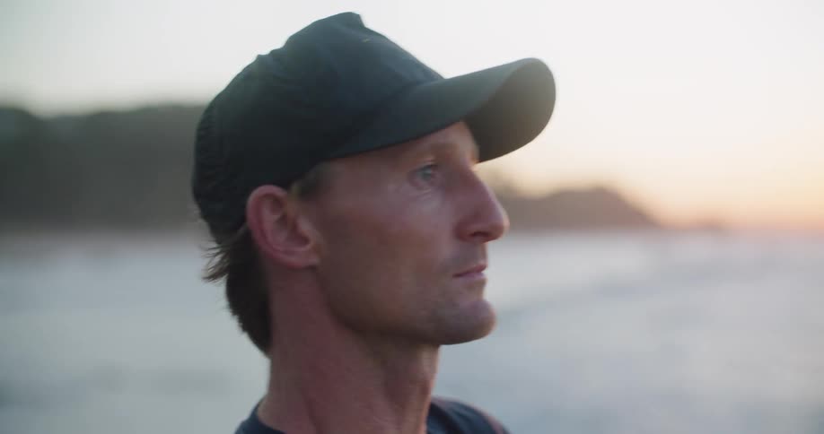 Man fishing on the coast of a beach near the ocean at sunset