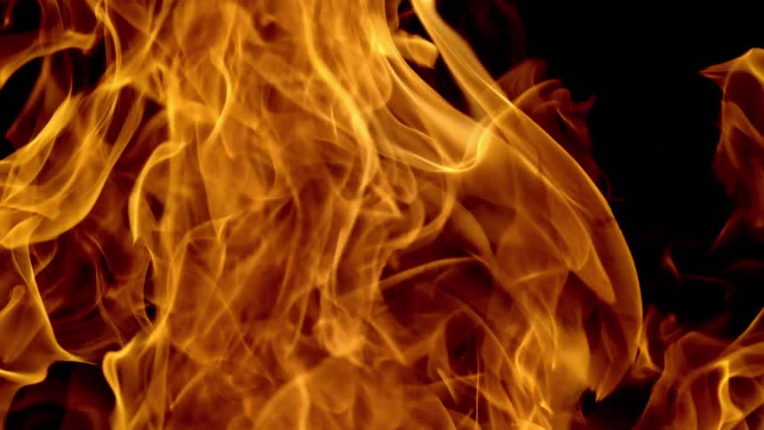 Large flames rise against a black background