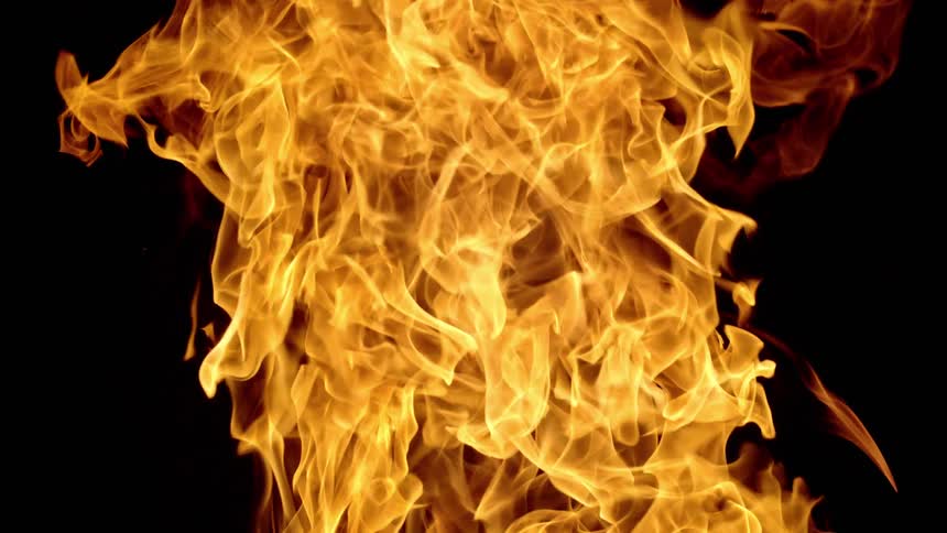 Orange flames flow and rise against black background