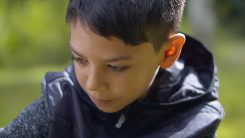 A young boy outside in a rain jacket in the daytime