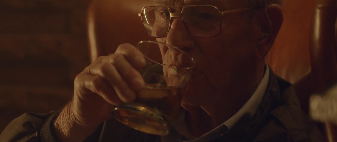 A man lifts a glass and takes a drink