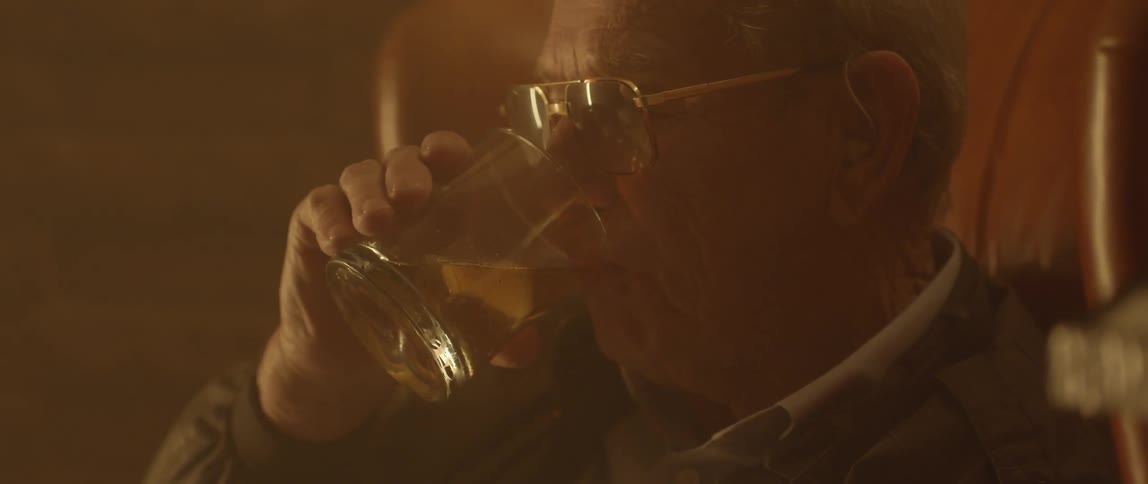 A man takes a drink from a glass