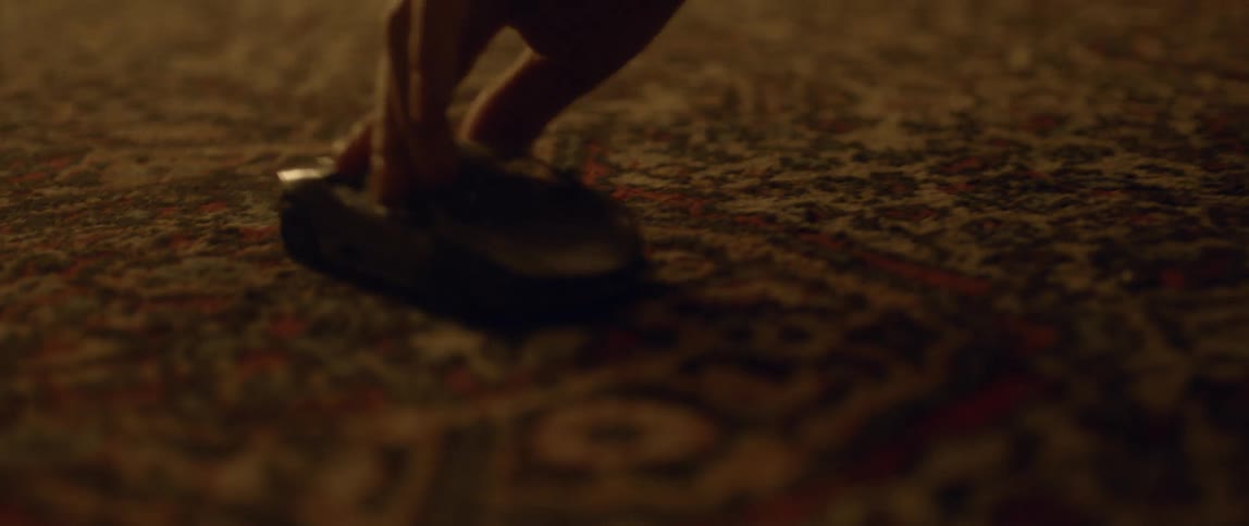 A hand moves a toy car across a carpet