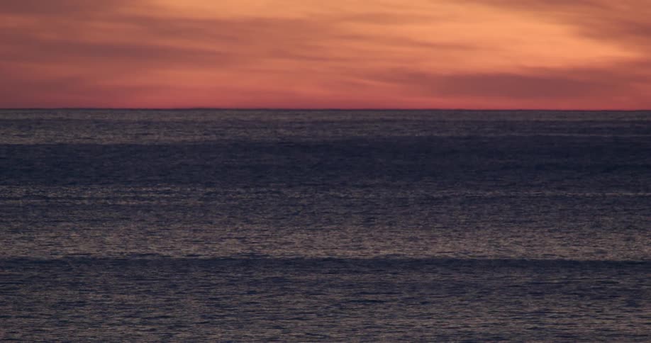 Ocean waves and surface shimmer under glowing orange clouds