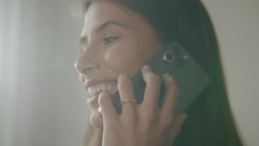 A woman smiles while talking on the phone