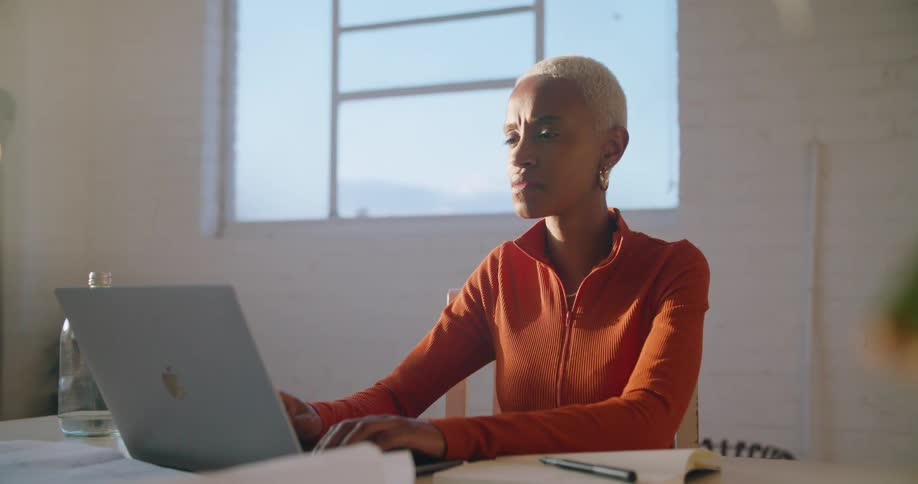 A woman is typing on her laptop in her office