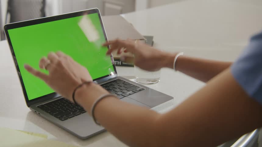 A woman presses buttons a laptop keyboard while sitting at a desk