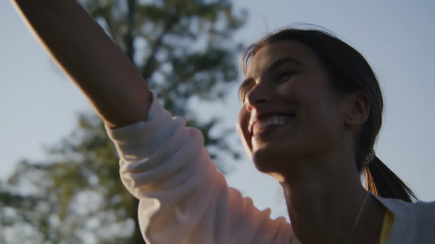 A woman smiles as she holds a yoga pose outdoors