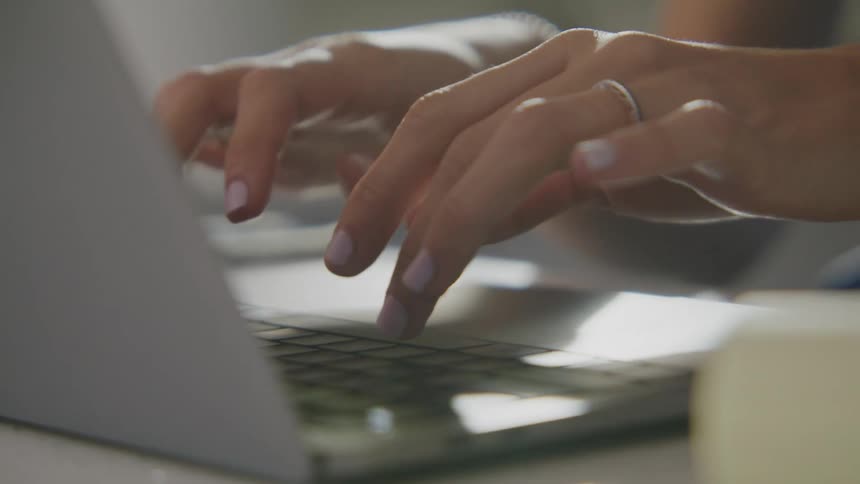 A woman is typing on a laptop keyboard