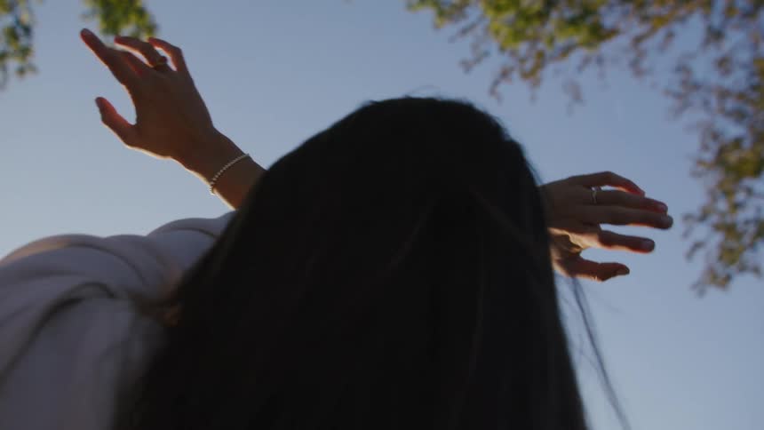 A woman reaches her arms up while stretching outside