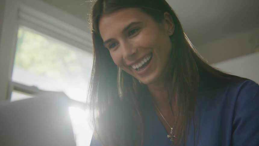 A woman smiles and laughs as she looks at her laptop