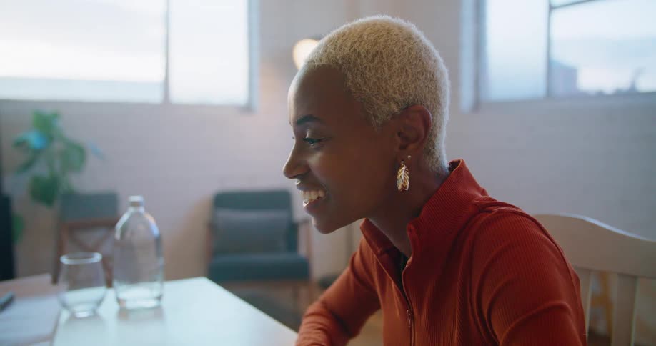 A woman smiles and waves while sitting at her desk at an office downtown