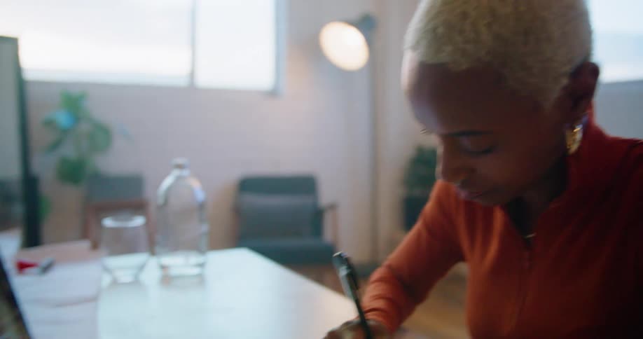A woman in a room video chatting a man on a laptop with a wall and a window in the background