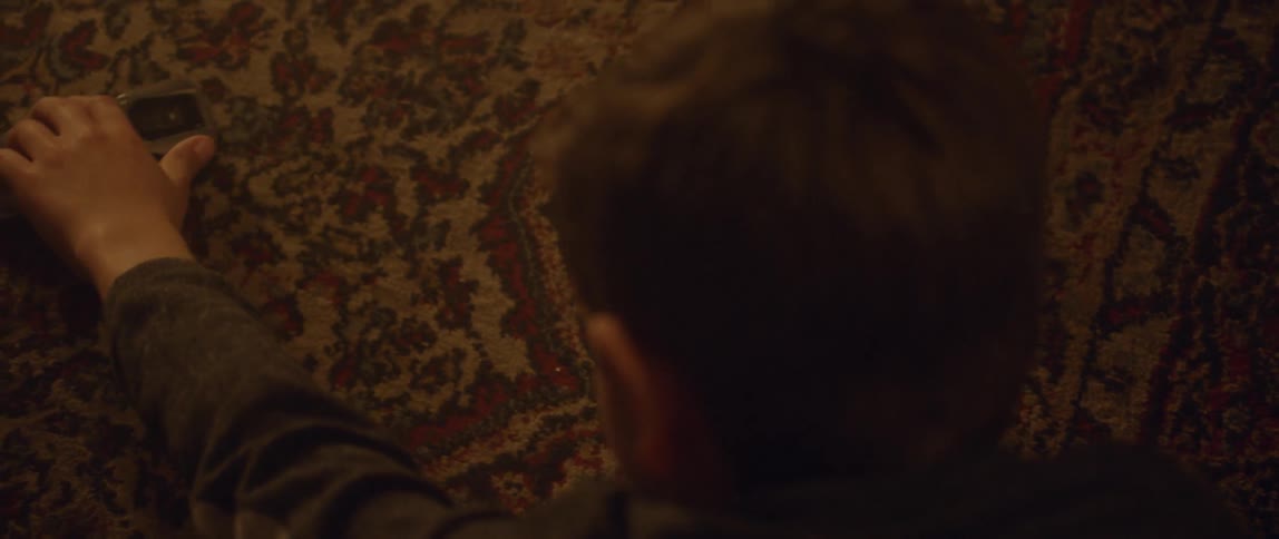 A child pushes a toy car on a carpeted floor