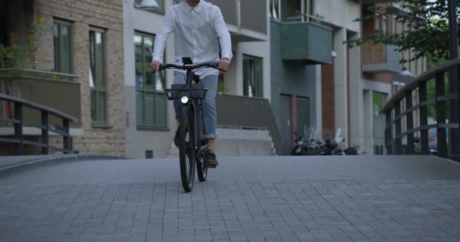 A man rides his bicycle over a pedestrian bridge