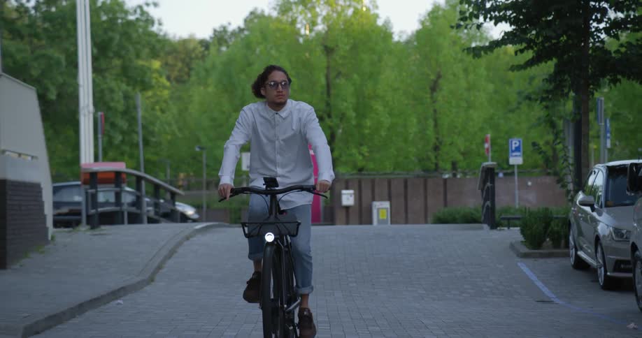A man rides a bike on a cobblestone city street