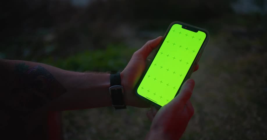 Tattooed man stands outdoors viewing mobile phone