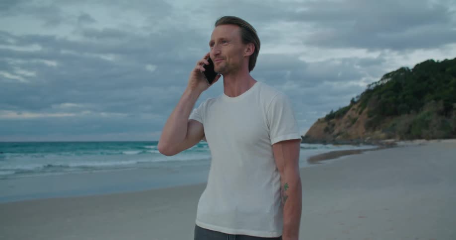 A man talking on a phone on a beach
