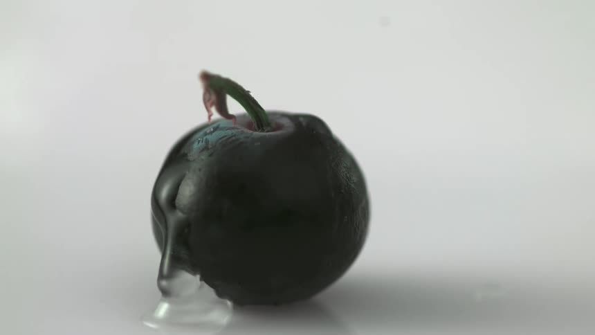 A drop of water falls off a green fruit and pools