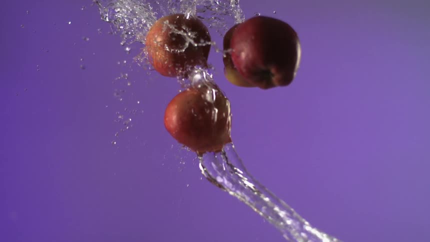 A stream of water splashes onto falling apples