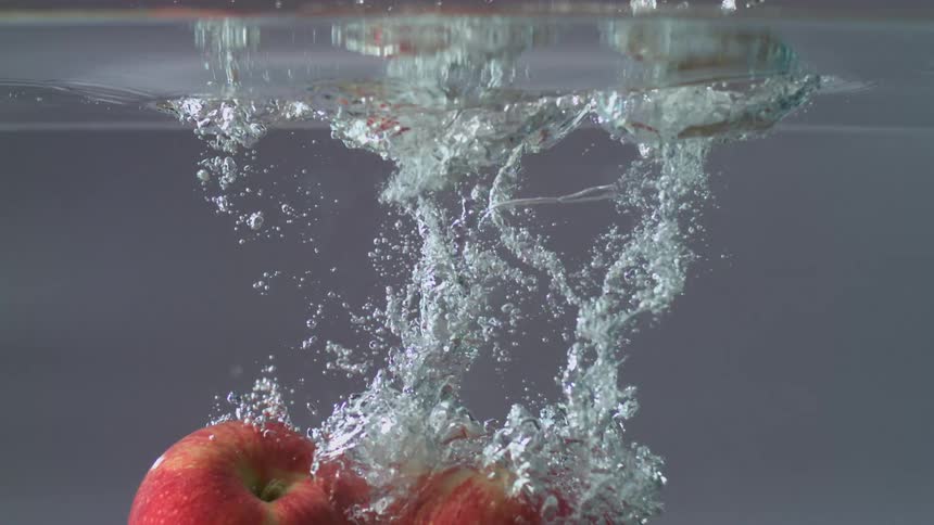 Two apples are dropped into the tub of water