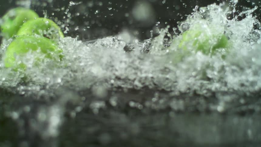 Green apples are rolling and splashing in water