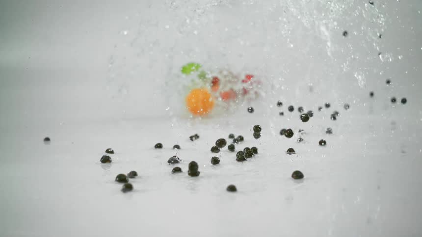 Blueberries splash through water as they fall followed by apples and oranges