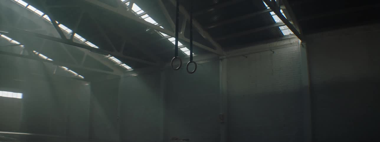 Gymnastic rings hang from the ceiling of gym in an open hangar