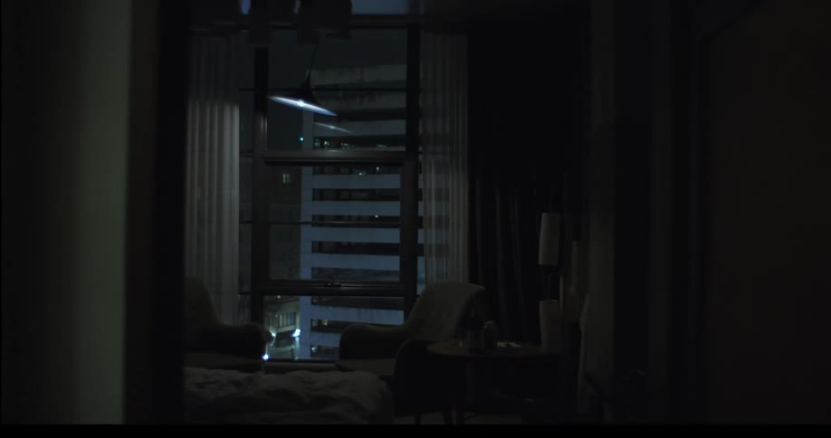 A light fixture sways back and forth in front of a window