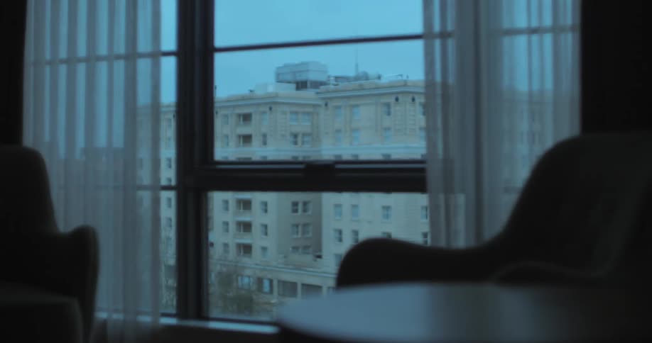 A room with a table and chairs with a wall and window in the background