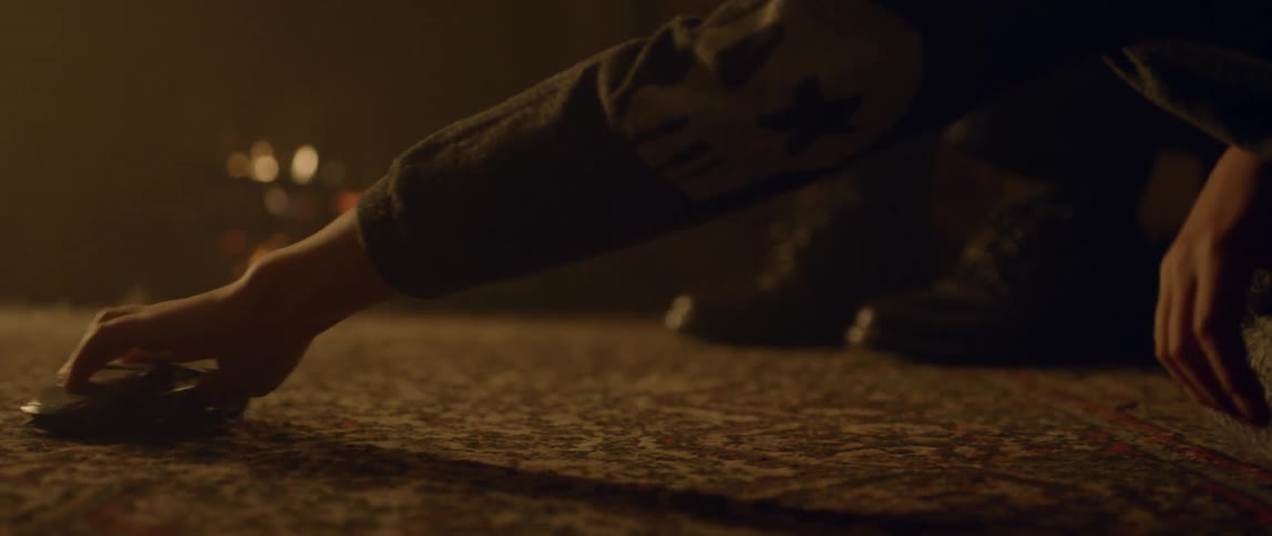 Hand slides an object across the floor with a fireplace in the background