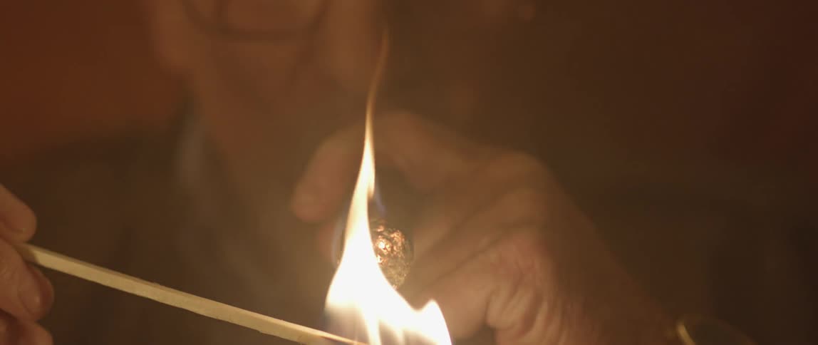 A man lighting his cigar from a long match