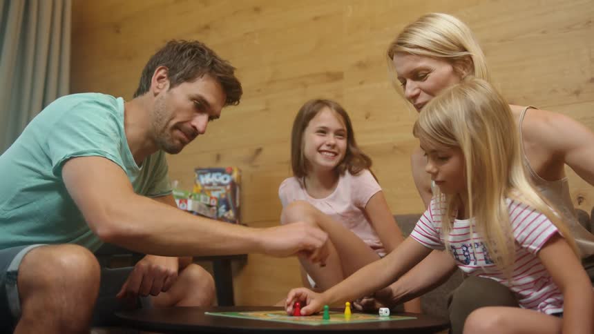 A family is sitting on a couch playing a board game