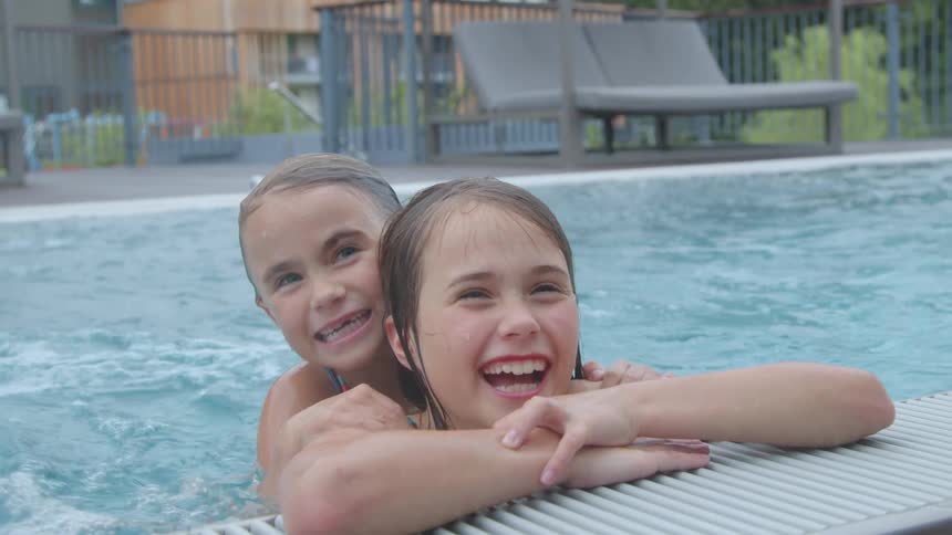 Two girls swimming in a pool and playing